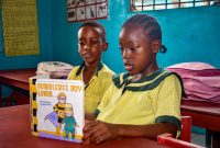 Two children in Monrovia, Liberia deeply engrossed in a book inside their classroom.