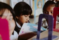 Group of children reading books together in a classroom setting.