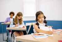 Young students focusing on their studies at desks inside a classroom.