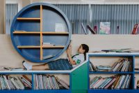 A young girl in a school uniform relaxes and reads in a modern library setting.