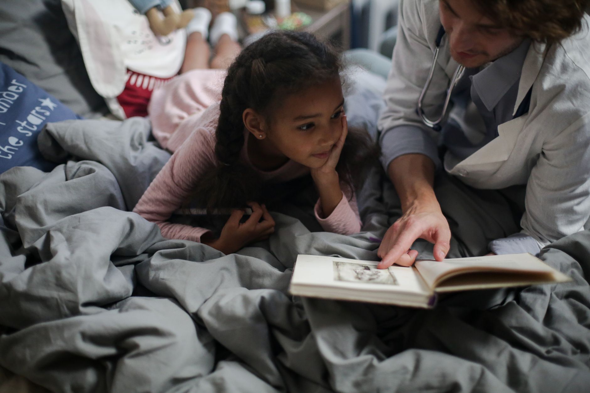 A father and daughter enjoy quality time reading a book together in a cozy setting.