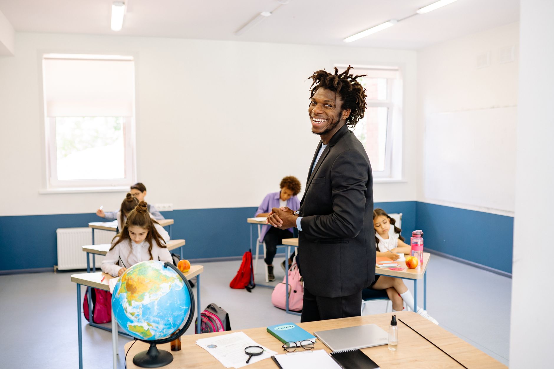 Teacher engaging with students in a bright classroom, promoting a positive learning environment.