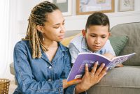 A mother reading a book with her young son on a comfortable couch indoors.