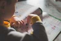 Young child coloring in a workbook, illustrating focus on early childhood education.